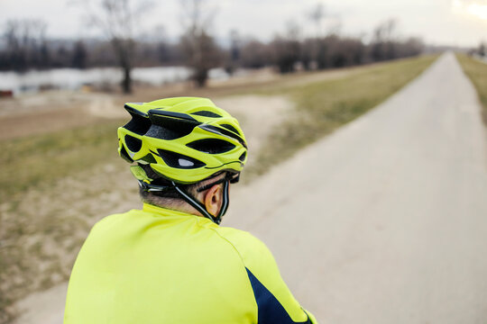 Rear view of a senior bicycle rider riding a bike in nature.