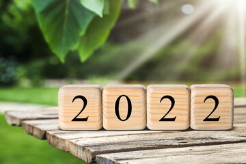 Happy New Year 2022 concept with wood cube block and nature background