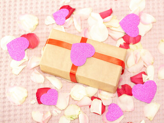 Rose petals on a white background. A gift on Vlentin's day, on his birthday. A gift in craft paper.