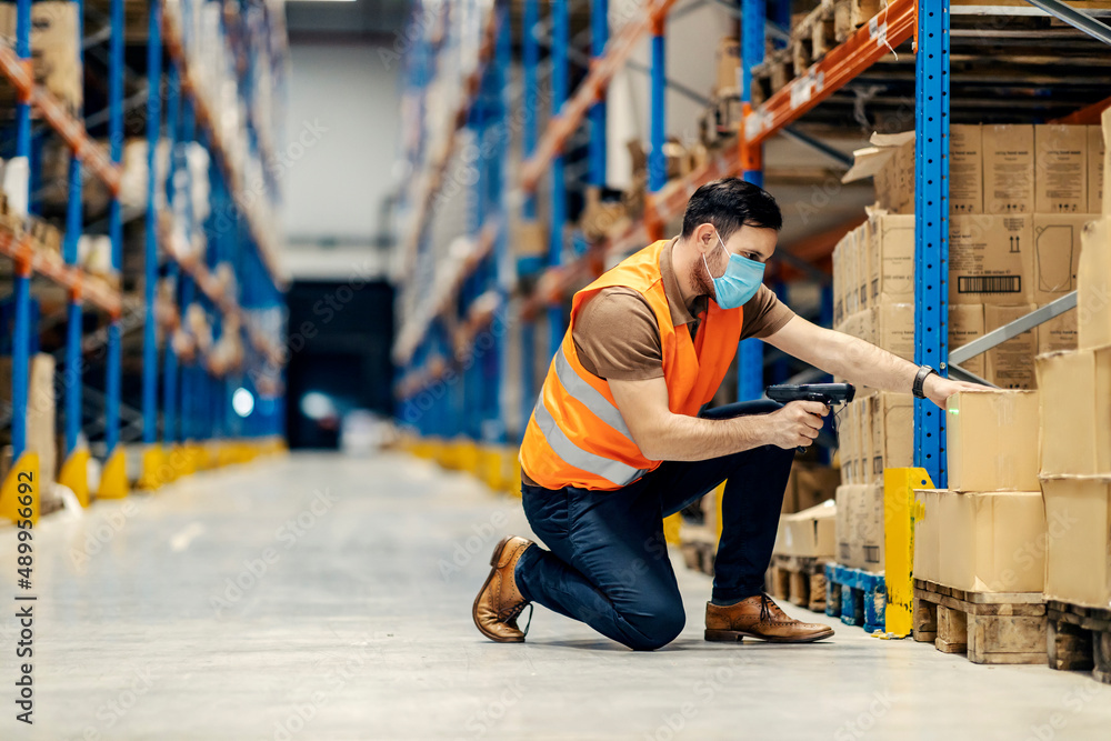 Sticker A focused inspector with qr and bar code scanner kneeling and scanning boxes in warehouse.