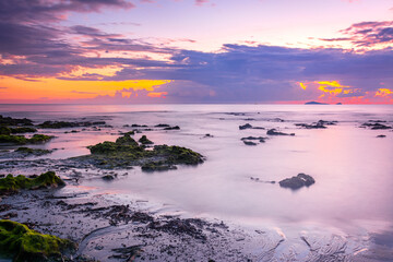 Obraz premium sunset landscape on the beach rocks in foreground