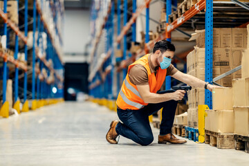 A focused inspector with qr and bar code scanner kneeling and scanning boxes in warehouse.