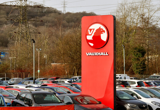 Treforest, Wales - February 2022: Sign Outside A Vauxhall Car Dealership With Used Cars For Sale Parked On The Garage Forecourt