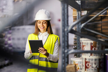 Female supervisor using tablet for data entry in warehouse.