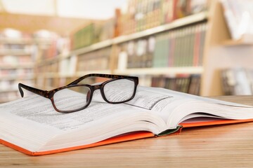 Old books, reading glasses on the wooden desk