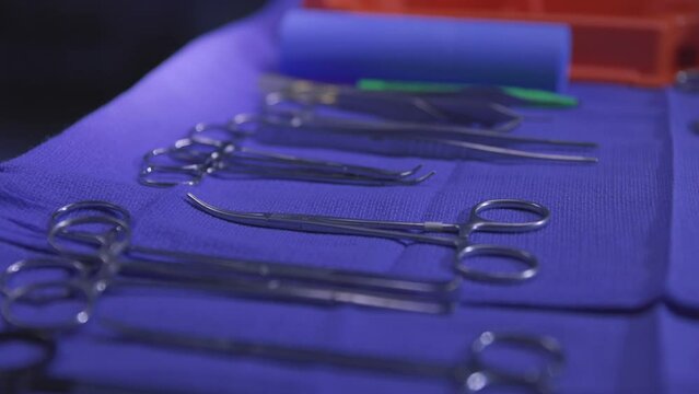 Surgical Instruments on Tray Close Up Pull Back. sanitized surgical instruments on a tray with blue cloth for operation moving away close up