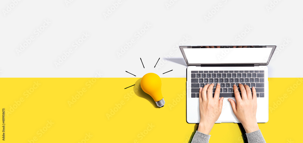 Sticker person using a laptop computer and a light bulb - flat lay
