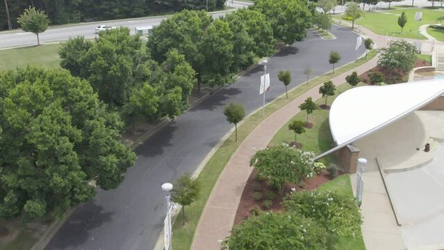 Flying over street lined with trees on both side to busy street