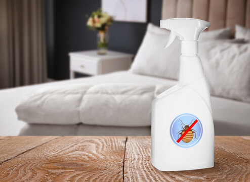 Anti bed bug spray on wooden table in bedroom. Space for text