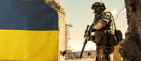 Ukrainian Soldier military in the war with a weapon in his hands. The flag of Ukraine is painted on...