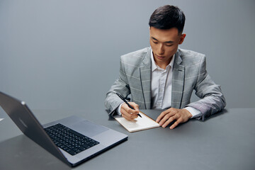 manager sitting at a desk in front of a laptop work writing in a notebook executive