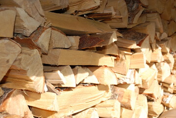 A stack of chopped firewood stacked on top of each other. Birch firewood of various shapes and sizes. stacked in several layers on top of each other. The layers are perpendicular to each other.