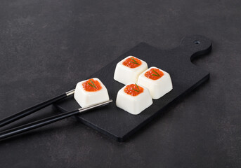 Small Cottage cheese cream pudding with red caviar on a serving board. Dark gray background