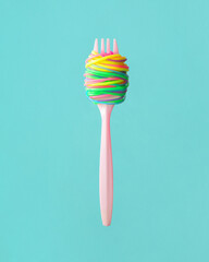 Creative food concept. Minimalistic composition with fork and fun spaghetti on mint background. Eating tasty colorful pasta dish idea.