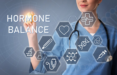 Doctor pointing at virtual screen with inscription Hormone Balance and digital icons on light grey...