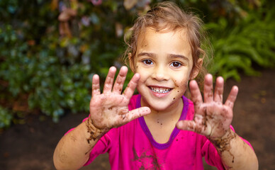 You have to get your hands dirty. Shot of a little girl showing her muddy hands while out playing.