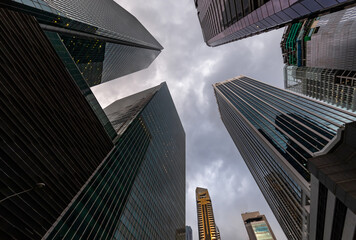 Fototapeta na wymiar Glass Facades of skyscrapers of the financial district of Singapore on a cloudy evening, bottom view, wide lens, city center, building of large companies without logos