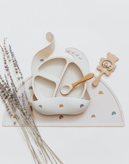 Flat lay composition with silicone set tableware for baby, bibs and plate on beige background. Serving food. Concept of kids menu, nutrition and feeding