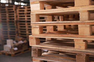 Many empty wooden pallets stacked in warehouse, closeup