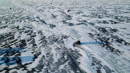 Flying over the frozen lake with ice fishing huts on the frozen surface. A very cold day to be...