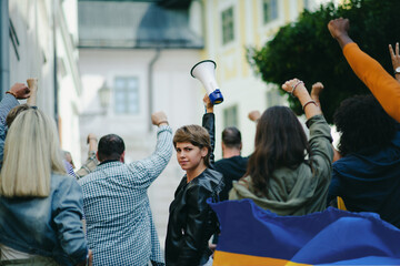 Crowd of activists protesting against Russian military invasion in Ukraine walking in street.