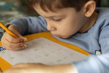 toddler doing homework by writing letters and numbers in notebook