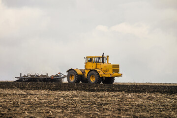 Wheeled tractor pulls the disc harrow