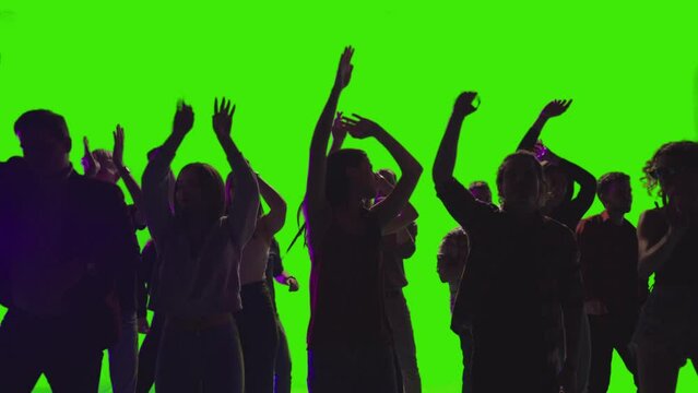 Overcrowded group of people are dancing dancing together with hands raised in slow-motion on greenscreen