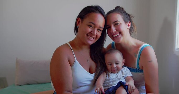a lgbt lesbian couple plays with their baby on the bed in the bedroom