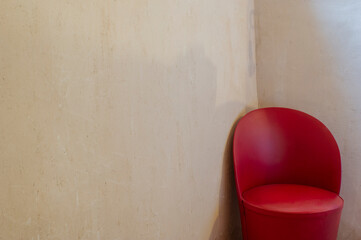 Butaca roja de piel setentera en parede de cemento liso
