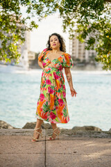 Beautiful woman posing in a floral dress by the water. She is in a Miami Beach scene