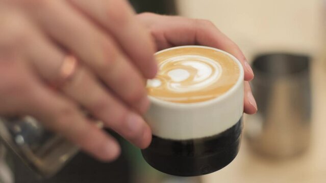 A Flat white being finished off with some latte art in the shape of a Florette