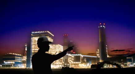 Fototapeta na wymiar Silhouette of an engineer or worker pointing at a factory smokestack.