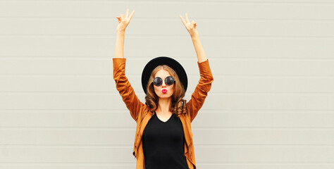 Portrait of stylish woman blowing her red lips sending sweet air kiss wearing boho style on gray background