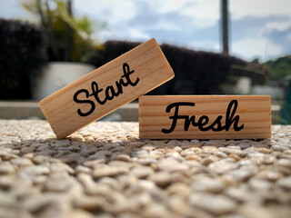 Text on wooden blocks - Start fresh. With blurred park background. Motivational concept.