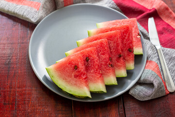 Sweet juicy red watermelon on wooden table in the grey plate