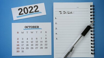 To do list text written on notepad for October month with pen and blue background. 2022 new year concept.