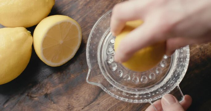 Hand squeeze lemon juice glass squeezer top down close up slow motion
