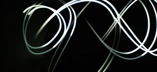 Closeup of Neon white Light curve pattern waves Abstract pattern flowing in a isolated black background made using Light painting technique called Long exposure.