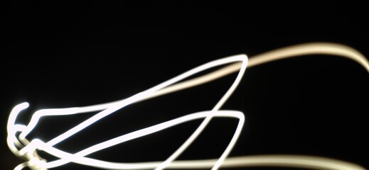 Closeup of Neon white Light curve pattern waves Abstract pattern flowing in a isolated black background made using Light painting technique called Long exposure.