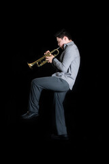 Young teenager energetically playing trumpet on black background