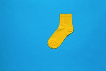 Bright yellow sports sock on a blue background. Flat lay.