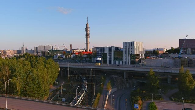 Helsinki.Finland-August 30.2021: Beautiful aerial shot of a train driving through the downtown of Helsinki. City transport. Awesome cityscape. Cars driving by. Drone slowly moving backwards.