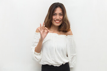 Young asian woman smiling and making OK sign with hand gesture.
