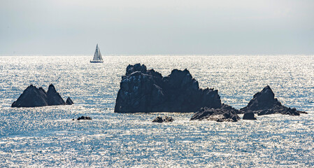 Cornish fishing boats and pinnacles of rock backlit by summer sunlight, protruding from the sea...