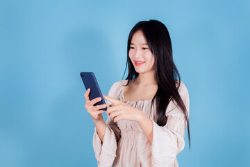 Portrait of smiling asian woman using a smartphone on blue background