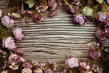 Frame of flowers with wooden banner for text on wooden background