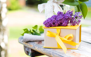 Gift box with yellow ribbon and lilac bouquets. A greeting card.