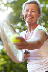 Ive had years of practice to perfect my serve. Smiling senior woman getting ready to serve - Tennis.