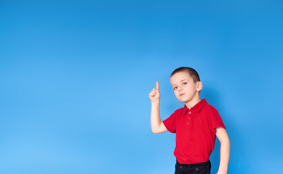 Portrait of a happy little boy on a blue background with thumbs up - The concept of childhood, growing up and achievements - front view, space for text
